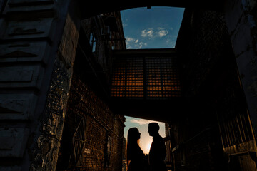 Romantic couple kissing in the city. Silhouette couple kissing over sunset background.