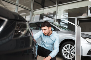 Business man inspects a new car at  dealership