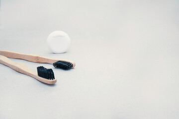Daily oral care. Two natural eco wooden toothbrushes and dental floss on a light background.
