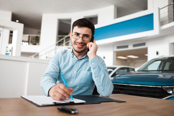 Auto dealership employee talking on the phone and writing