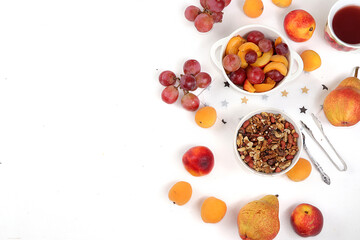 Useful breakfast, food for children, fruit salad with peaches, pears, granola, grapes and flower tea on a bright table. The concept of healthy and natural food. selective focus