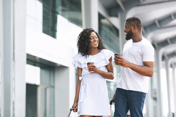 Fototapeta premium Happy Black Man And Woman Walking With Coffee Near Airport Building