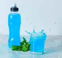 bottle of isotonic energy drink splash and glass with fresh mint leaves