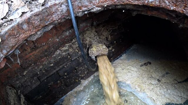Plumber cleans clogged pipes in outside. The plumber cleans the pipes with equipment.