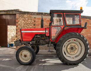 Red tractor parked in rural village.