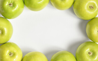 Oval frame of green apples with free text space in the center on a white background