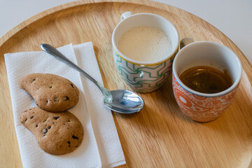 Wooden Plate Prepared for Breakfast with Milk Coffee Silver Spoon and Couple Chocolate Cookies