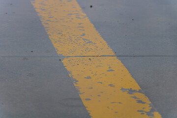 Fototapeta premium Yellow Strip on Grey Concrete During Rain Day