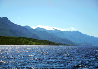Beautiful landscape with wavy blue sea in the foreground and mountain hills in the background