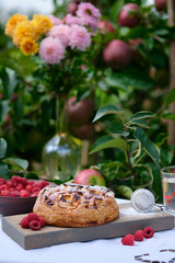 Apple pie on an old wooden table under an apple tree in a village. Bright sunny day and tasty homemade dessert with compote.