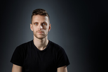 Obraz premium Young man, showing no emotions on black background.