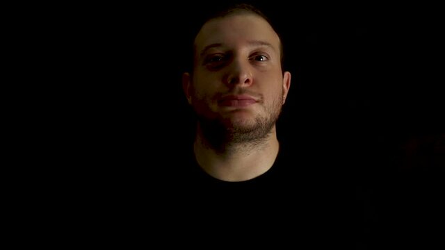 Portrait of young, bored man on black background. Tired and outworn concept.