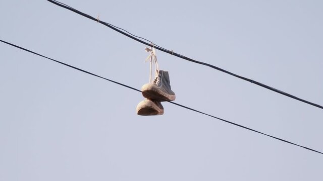 sneakers hanging on wires against the blue sky