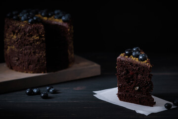 Slice of chocolate cake with cherry and blueberry on a wooden table. Delicious festive dessert. Fresh and beautiful cake.