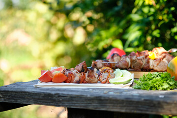 Freshly cooked barbecue and vegetables on a wooden table. Summer lunch in nature. Tasty meat dish cooked on the fire.