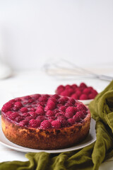 Morning breakfast with raspberry cheesecake. Dessert and raspberries in a plate on a white wooden table.