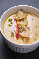 Pumpkin cream soup with breadcrumbs, hot pepper and thyme, garnished with pumpkin seeds.