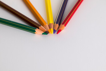 Colored pencils, united at point, on white background
