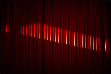 Drum with red fiber cords in PVC with partial light making an abstract view