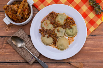 Sorrentinos, stuffed pasta, with sauce on wooden table