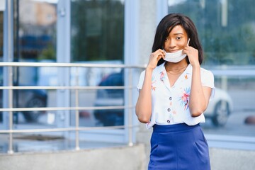 African american young volunteer woman wearing face mask outdoors. Coronavirus quarantine and global pandemic.