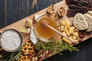 Tasting different types of cheese, honey, nuts, herbs, ciabatta and sausage. Several varieties of cheese on a wooden board. Delicatessen for a romantic dinner. Top view.