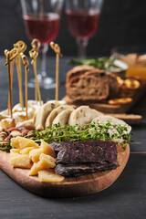 Delicious snacks and wine. Several varieties of cheese, nuts, ciabatta and sausage on an old wooden table. Food for a romantic dinner.