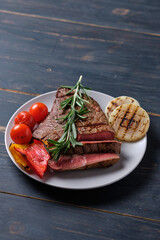 Sliced freshly cooked blood steak served with grilled vegetables on a plate. Close-up.