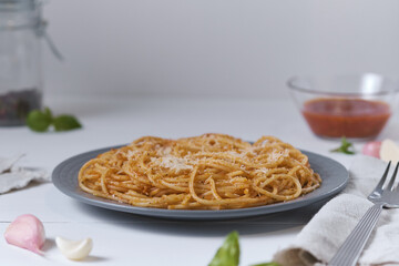 Fototapeta premium Spaghetti with tomato sauce and parmesan. Pasta on a white wooden table. Italian dish for lunch.