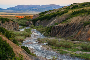 Fototapeta na wymiar Summer landscape with a river in the gorge among the rocks and tundra. Wilderness beyond the Arctic Circle, located away from settlements. Hiking to the far north. Chukotka, Siberia, Far East Russia.