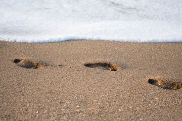 Footprints in the sand on the sea beach near the water edge