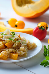 Pumpkin risotto garnished with fresh parsley and parmesan. Italian dish on a white table.