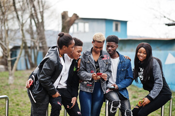 Young millennials african friends with mobile phones. Happy black people having fun together....