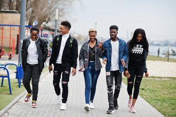 Fototapeta premium Young millennials african friends walking in city. Happy black people having fun together. Generation Z friendship concept.
