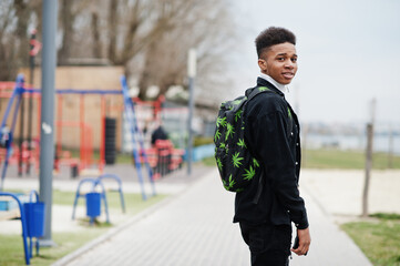 Young millennial african boy walking in city. Happy black man with marijuana backpack. Generation Z concept.