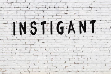 Word instigant painted on white brick wall