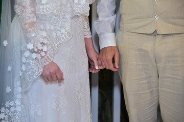 The bride and groom hold hands during the ceremony.