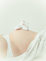 pregnant woman holding baby shoes - obrazy, fototapety, plakaty