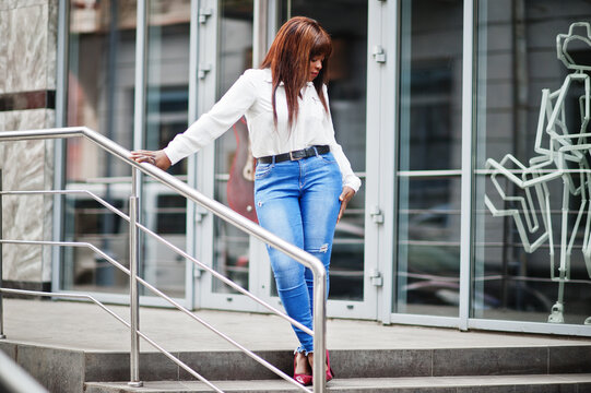 Cute african american model in white shirt and jeans pants posed outdoor.