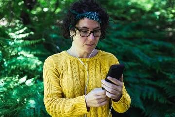 mujer en el monte con telefono y auriculares