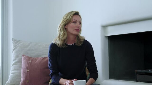 MS Woman holding mug and listening / Majorca, Spain