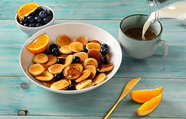 Close up of mini pancakes in white plate on light green blue background