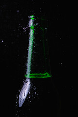 Obraz na płótnie Canvas Water splashes crash into a fogged cold bottle of beer on a black background.