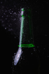 Water splashes crash into a fogged cold bottle of beer on a black background.