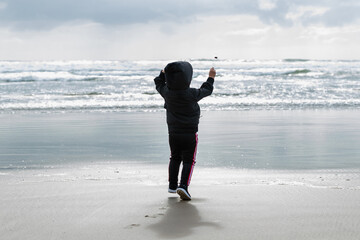 Young boy on the beach throwing a rock into the ocean