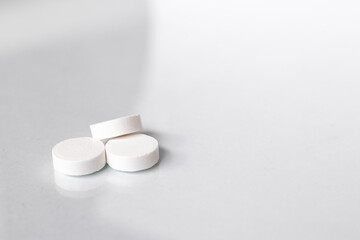 Fototapeta na wymiar Three white pills on a white background close-up. Macro photo on the subject of pharmaceuticals and medicine