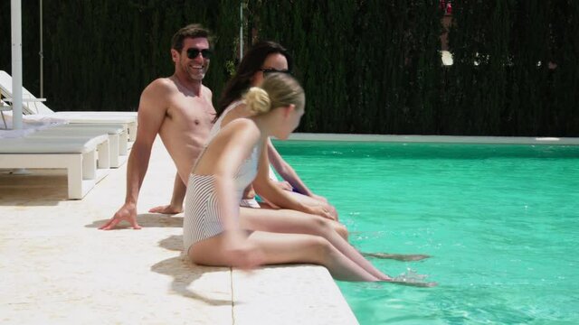 MS Family with children (12-13, 14-15) sitting on poolside and splashing / Majorca, Spain