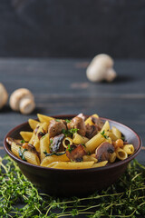 Vegetarian pasta with mushrooms, chickpeas, spinach, spices and herbs. Italian pasta in a bowl on an old wooden table.