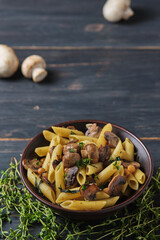 Vegetarian pasta with mushrooms, chickpeas, spinach, spices and herbs. Italian pasta in a bowl on an old wooden table.