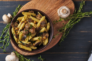 Vegetarian pasta with mushrooms, chickpeas, spinach, spices and herbs. Italian pasta in a bowl on an old wooden table. Top view.